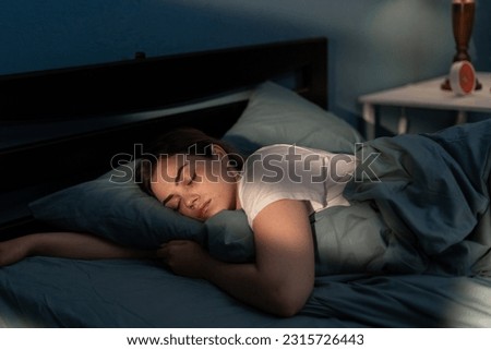 Young female sleeping peacefully in her bedroom at night. Relaxing at nighttime. Copy space