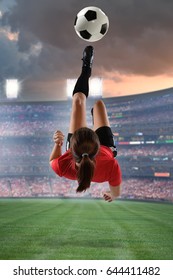 Young Female Soccer Player kicking the ball in mid-air inside stadium