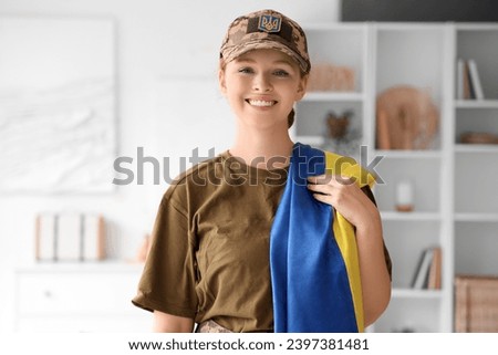 Young female soldier with flag of Ukraine at home