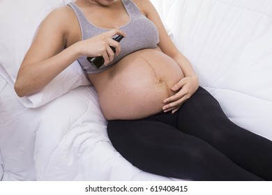 Young Female Spraying Mineral Water or Perfume on Her body, Treatment, Skin, Beauty, Cosmetic, Makeup, Healthy, Lifestyle concept. Pregnant Woman holding spray bottle of Mosquito Repellent