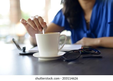 Young Female Stir Cup Of Coffee In The Morning At Cafe