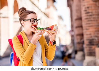 Young Female Student Eating Pizza On The Break Near The University In Bologna City In Italy