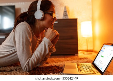 Young Female Student At Home.She Sitting In Her Living Room And Learning Online On Laptop.E-learning.