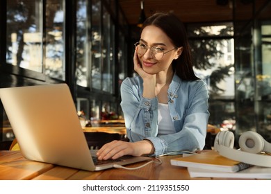 Young female student with laptop studying at table in cafe - Shutterstock ID 2119351550
