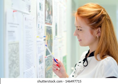 Young female student looking through job offers on board