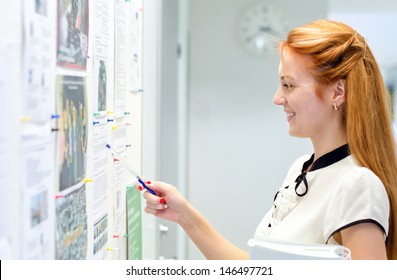 Young Female Student Looking Through Job Offers On Board