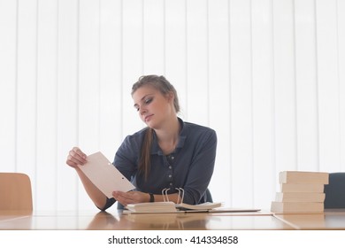 Young Female Student Reading File Index Card At Library Desk