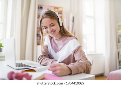 Young female student sitting at the table, using laptop when studying. - Powered by Shutterstock