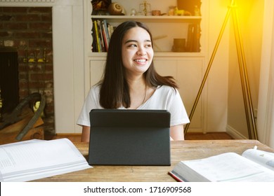 Young Female Student Smiles As She Studies During Learning From Home - Lock Down Pandemic - Indoors In Living Room - High School