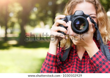 Young female student taking photos in the park with camera. Photography classes, education and remote working concept, copy space, closeup