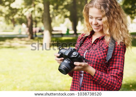 Young female student taking photos in the park with camera. Photography classes, education and remote working concept, copy space, closeup