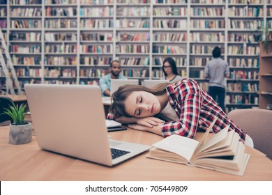 Young female student is tired and is sleeping at the desktop, her international focused classmates are studying in the ancient university library, sit at the table behind her, in casual outfits - Powered by Shutterstock