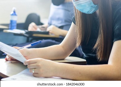 Young Female Student Wearing A Mask And Taking An Important Exam At School. 