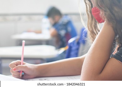 Young Female Student Wearing A Mask And Taking An Important Exam At School. 