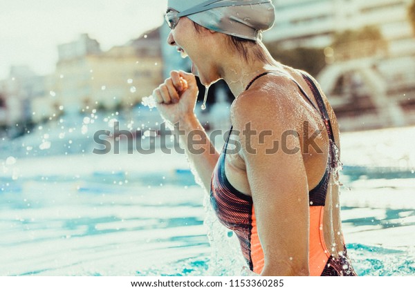 Young female swimmer celebrating victory in the\
swimming pool. Excited woman swimmer with clenched fist inside the\
swimming pool.