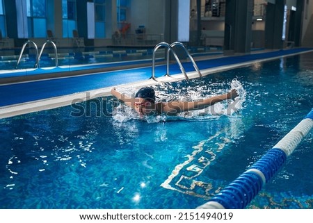Young female swimming the butterfly in the pool