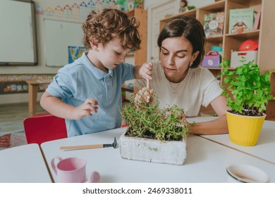 Young female teacher with boy taking care of potted plant in kindergarten. Selective focus. - Powered by Shutterstock