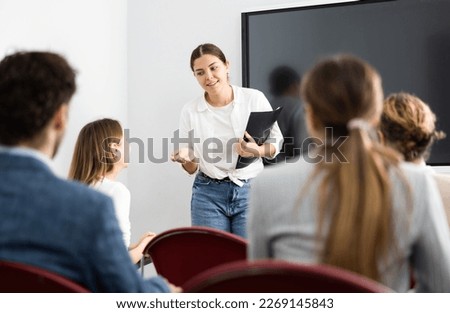 Young female teacher giving lecture to group of student