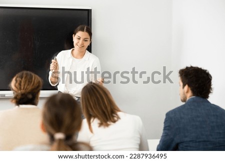 Young female teacher giving lecture to group of student
