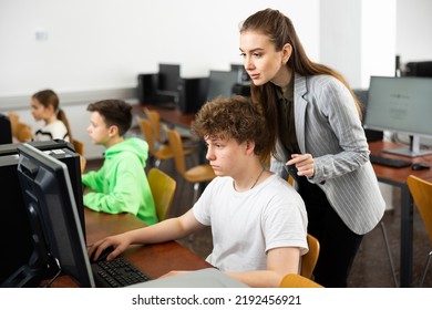 Young Female Teacher Helping Focused Teenage Student Studying For Exam In College Library Computer Lab..