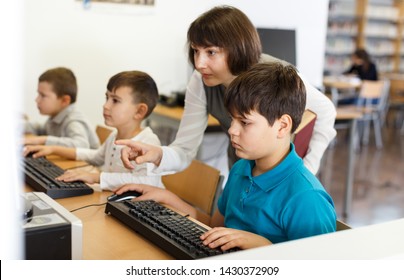 Young female teacher working with pupil in computer class of school library  - Powered by Shutterstock