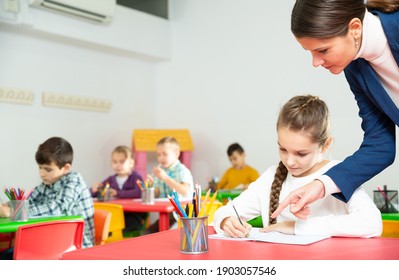 Young female teacher working with pupils in classroom at elementary school