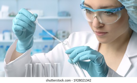 Junge weibliche Technikerin oder Wissenschaftlerin lädt flüssige Probe mit Plastikpipette in das Reagenzglas. Schmaler DOF, fokussieren Sie auf die Hand mit der Tube.