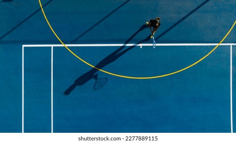 a young female tennis player in action on a brand-new court. This photo was captured with a drone to give a unique perspective on the game. Perfect for sports publications, athletic advertisements, an - Powered by Shutterstock