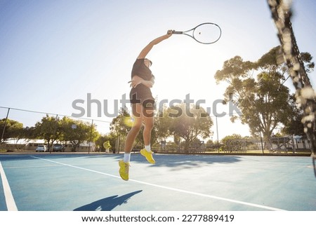  A young female tennis player in action on a brand new tennis court. This photo features stunning backlight and was taken with a wide-angle lens to bring you closer to the action. Perfect for sports 