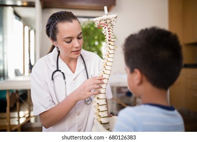 Young female therapist explaining boy with artificial spine at hospital ward - Powered by Shutterstock