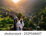 Young female tourist in Chinese traditional dress taking photos of beautiful sunset view of Wangxian Valley in Shangrao, China