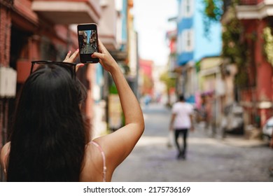 Young female tourist is exploring new city making photo on smartphone - Powered by Shutterstock