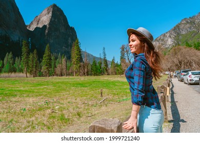A young female tourist in a hat enjoys mountain views in Yosemite National Park