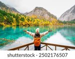 Young female tourist looking at beautiful autumn scenery landscape at jiuzhaigou national park in Sichuan, China