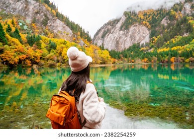 Young female tourist looking at beautiful autumn scenery landscape at jiuzhaigou national park in Sichuan, China