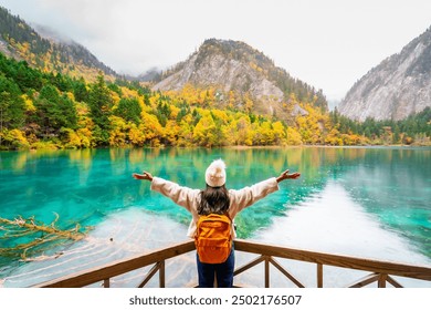 Young female tourist looking at beautiful autumn scenery landscape at jiuzhaigou national park in Sichuan, China - Powered by Shutterstock