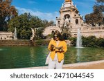 Young female tourist with paper map and phone visiting Ciutadella Park in Barcelona. Concept of travel, tourism and vacation in city, Traveling Europe