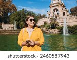 Young female tourist with phone visiting Ciutadella Park in Barcelona. Concept of travel, tourism and vacation in city. Use technology concept, Traveling Europe