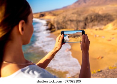 Young Female Tourist Photographing With Phone Beautiful Papagayo Beach On Lanzarote Island In Spain