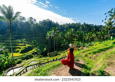Young female tourist in red dress looking at the beautiful tegalalang rice terrace in Bali, Indonesia