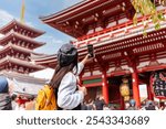 Young female tourist taking a photo of sensoji temple at Asakusa district in Tokyo, Japan