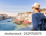 Young female tourist traveling in city in Venice, Italy, looking from Rialto Bridge in Venice, Italy.