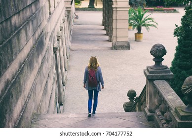 Young female tourist walks from the steps of a historic castle. A woman traveler in old european city. 
