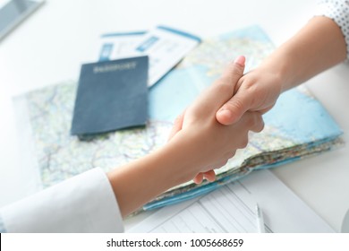 Young Female Travel Agent Consultant In Tour Agency With A Customer Handshake