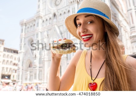 Young female traveler holding lampredotto sandwich in the center of Florence city. Lampredotto is a typical Florentine dish made from the stomach of a cow