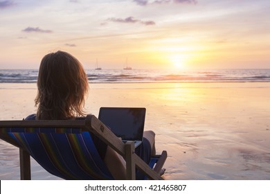 Young Female Traveler Writing Email On The Beach With Laptop Computer At Sunset