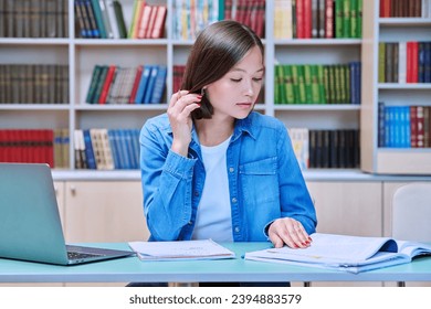 Young female university student studying inside library - Powered by Shutterstock