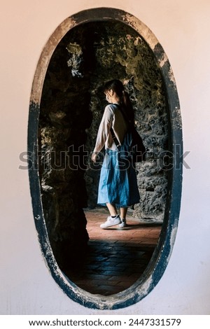 A young female visitor wearing a mask walks through an egg-shaped gate in the Lin Ben Yuan's Family Garden, a tycoon's estate in Qing Dynasty located in Banqiao District, New Taipei City, Taiwan.