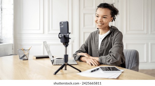 Young female vlogger creating content with smartphone and laptop, modern influencer. - Powered by Shutterstock