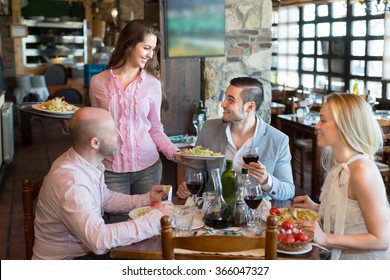 Young Female Waiter Serving Restaurant Guests. Selective Focus